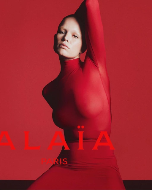 Fashion portrait: Woman in red bodysuit poses against matching background for ALAÏA Paris, creating a visually striking monotone.