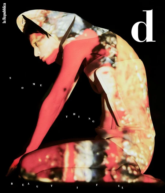 Dramatic fashion editorial featuring a kneeling adult female model with an abstract floral overlay, set against a stark black background.