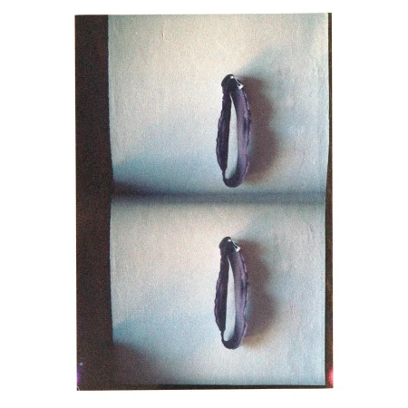 Still life studio shot of two violet bracelets on a gray surface with soft shadow, showcasing fashion accessories in a simple setting.