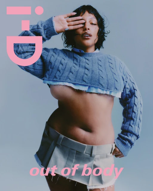 Magazine cover shot of a woman wearing a blue cropped sweater and khaki skirt, covering one eye with her hand, against a grey background.