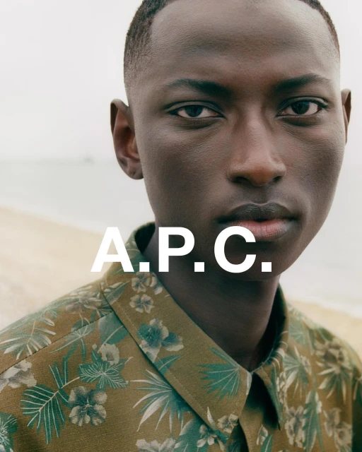 Close-up of an adult male wearing a patterned shirt on a beach with the A.P.C. logo in white. Fashion and portrait photography.