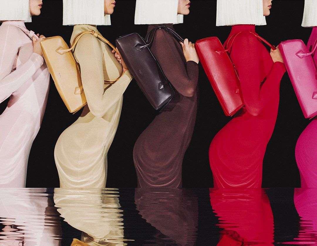 Fashion models in colorful dresses standing in water with reflections, showcasing dresses and handbags for a fashion campaign.
