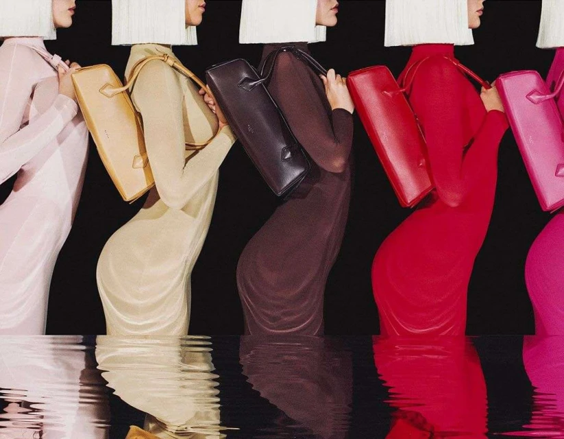 Fashion models in colorful dresses standing in water with reflections, showcasing dresses and handbags for a fashion campaign.
