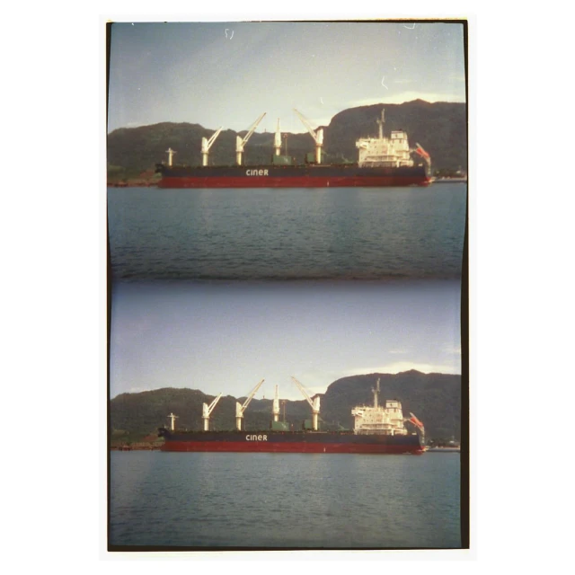 Cargo ship with cranes in harbor near green mountains under a clear sky. Commercial shipping transport and coastal landscape. 