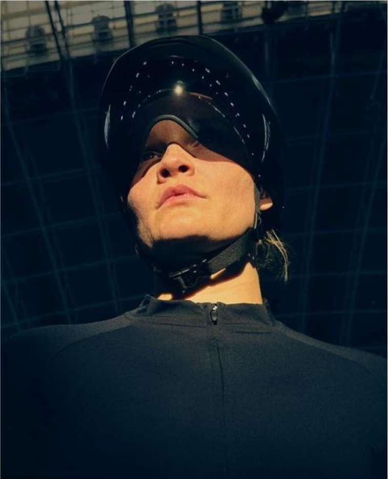 Person in black helmet and visor against geometric background. Eye-level shot with natural lighting emphasizes futuristic look.
