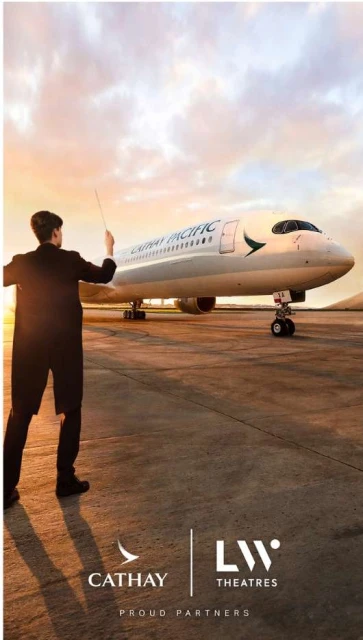 Airplane on the tarmac at sunset with a person in a suit standing in the foreground, near airport buildings and a warm-colored sky.