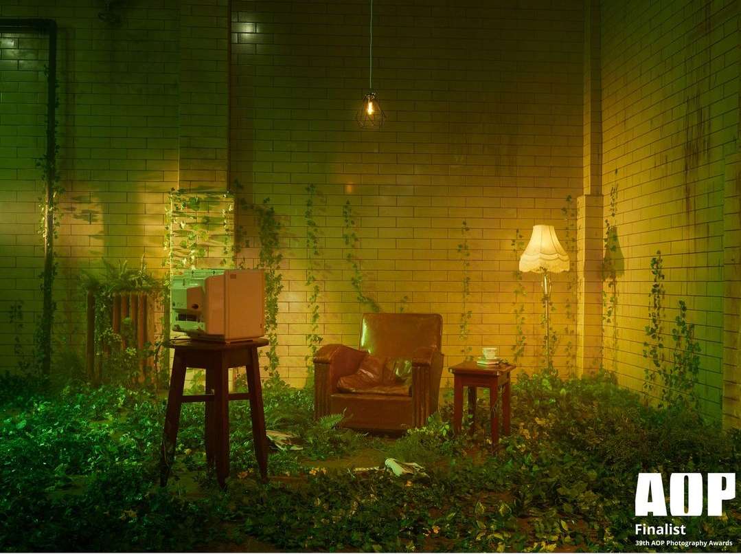 Vintage television sits on a wooden stool amid lush greenery in a room with exposed brick walls, illuminated by warm, ambient lighting.