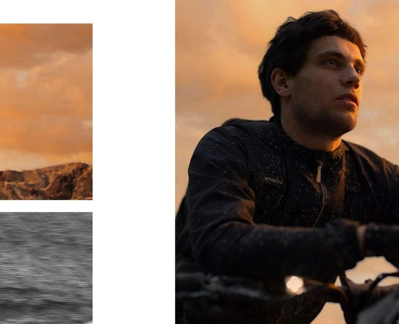 Adult male wearing black jacket gazes upward with an orange sky and rough terrain in the background in a medium outdoor shot.