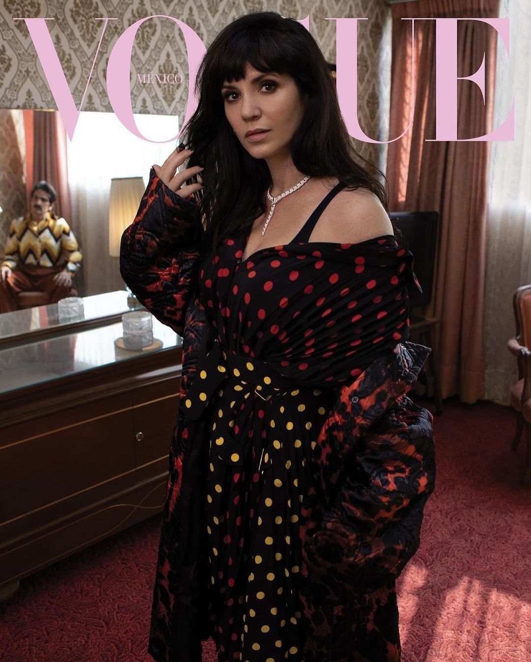 Magazine cover featuring a dark-haired woman in a polka dot dress and necklace, glancing towards the camera in an indoor setting.