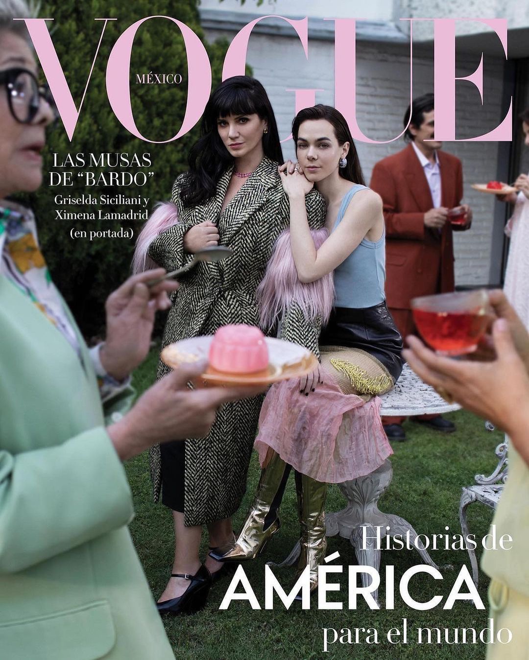 Vogue Mexico cover featuring two women in stylish outerwear, one seated in a pink skirt and gold boots in a garden setting.