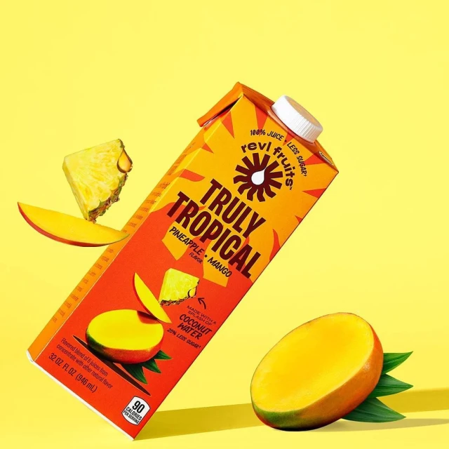 Tropical juice box with pineapple and mango flavor. A healthy drink option featuring slices of fresh fruit on a yellow background.