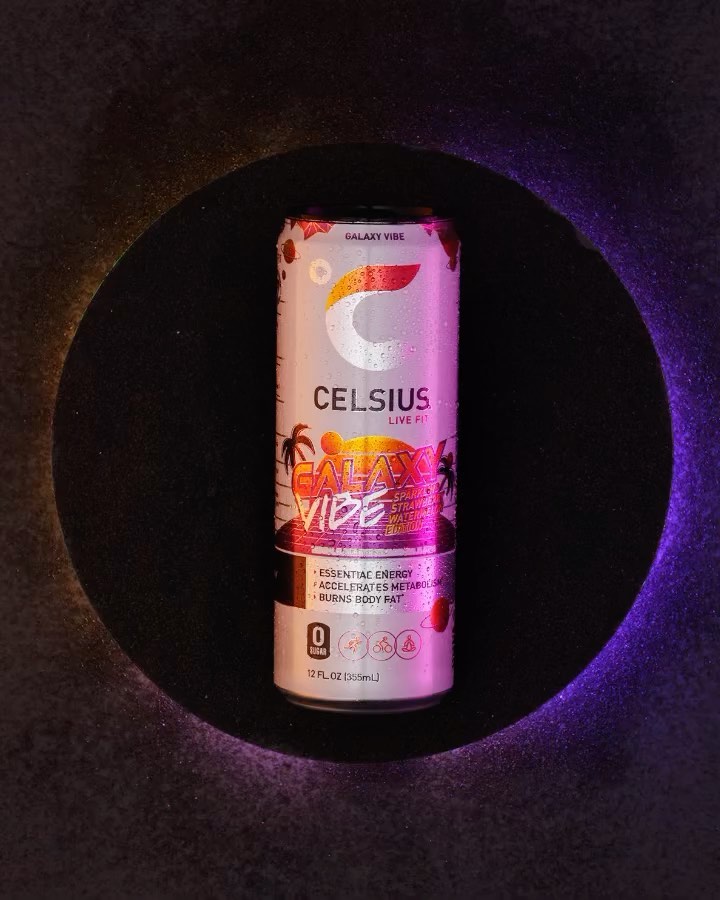 A can of Celsius energy drink with a 'Galaxy Vibe' design sits against a dark backdrop, illuminated by blue and orange light.