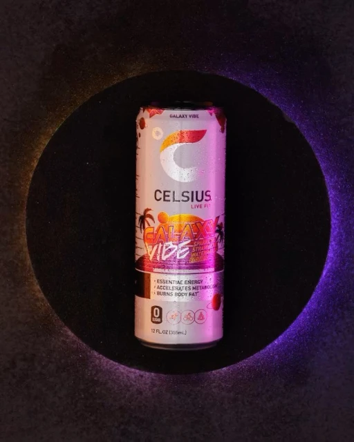 A can of Celsius energy drink with a 'Galaxy Vibe' design sits against a dark backdrop, illuminated by blue and orange light.