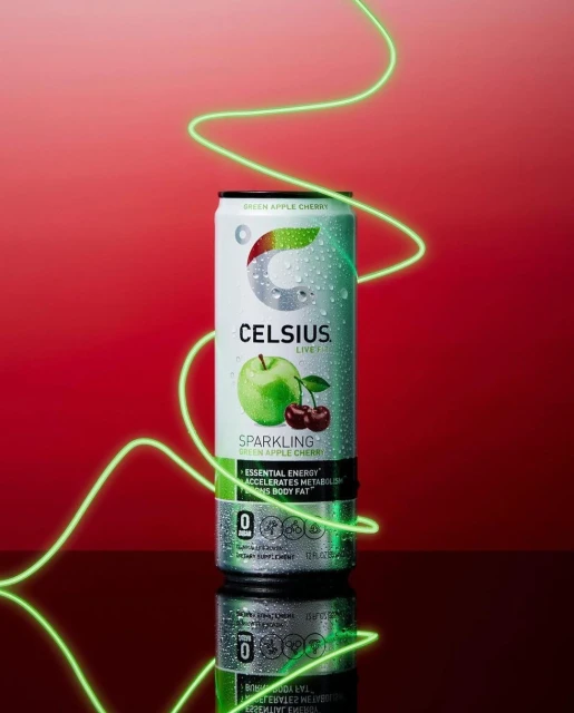 Celsius brand energy drink can featuring green apple cherry flavor with studio lighting and a red background.