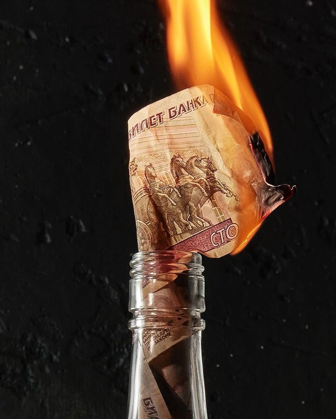 Burning Russian Ruble banknote in a glass bottle against a dark background with fire flames, studio shot. Economic crisis or protest.