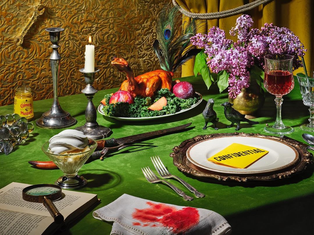 Dinner table scene features a roasted bird, antique silverware, crime scene evidence, magnifying glass, candle, and dark moody lighting.
