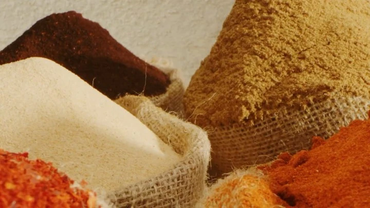 Close-up of spices in burlap sacks in warm lighting. The image highlights the textures and colors of the spices and rough fabric.