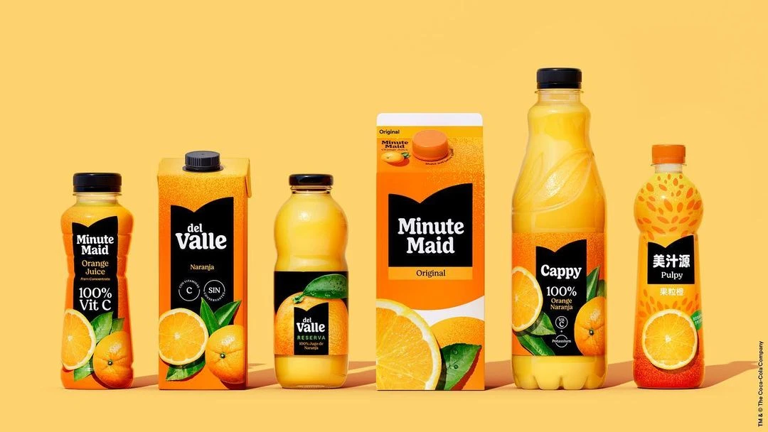 Variety of branded orange juice containers including Minute Maid, del Valle, and Cappy lined up on a seamless yellow background.