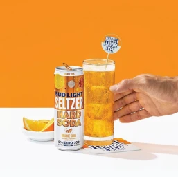 Tall can of Bud Light Seltzer Hard Soda next to a tall glass of orange beverage with a garnish stick and orange slices.