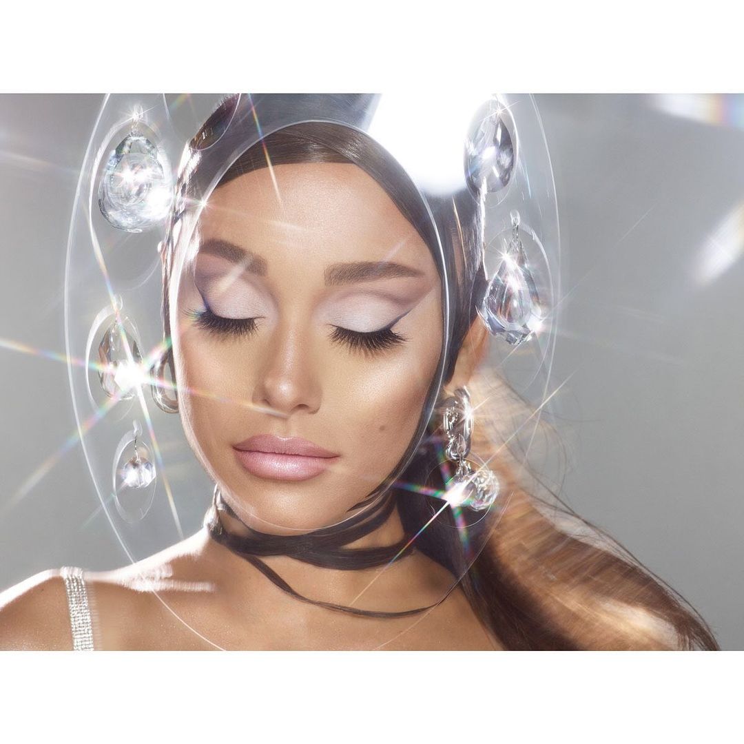 Close-up of an adult female with closed eyes and pale pink lipstick wearing silver hoop earrings and a diamond choker necklace.