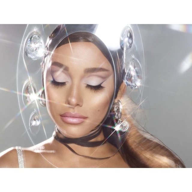 Close-up of an adult female with closed eyes and pale pink lipstick wearing silver hoop earrings and a diamond choker necklace.