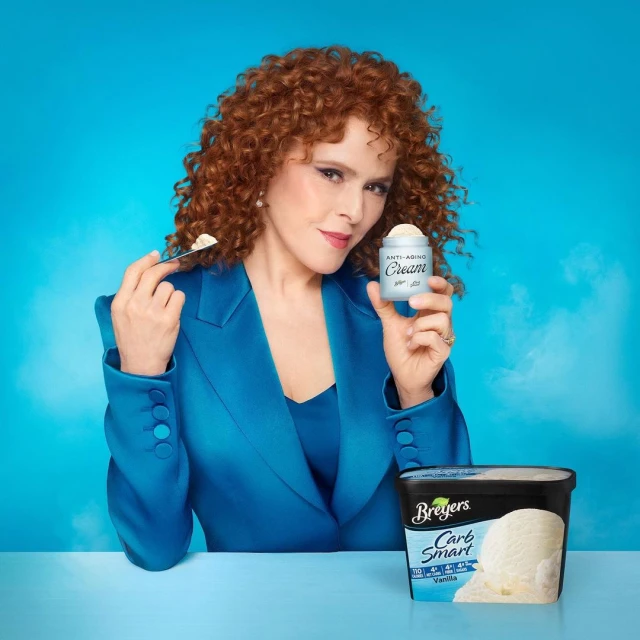 Bernadette Peters posing with ice cream and anti-aging cream against a blue background for Breuer's Carb Smart vanilla.