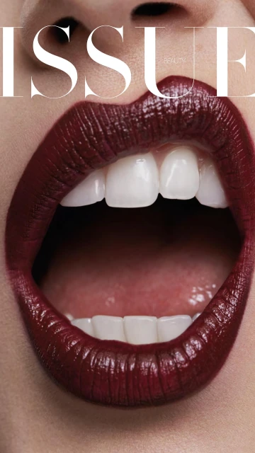 Close-up shot of a woman's open mouth with deep red lipstick and white teeth, featuring the magazine title ISSUE.