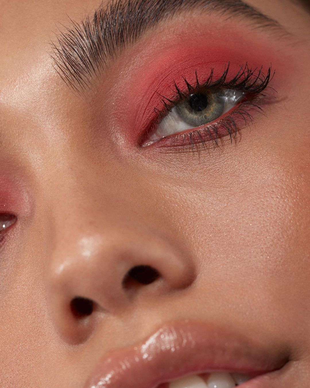 Close-up portrait of a woman with red eyeshadow, emphasizing beauty and makeup artistry in a studio setting, showcasing cosmetic application.