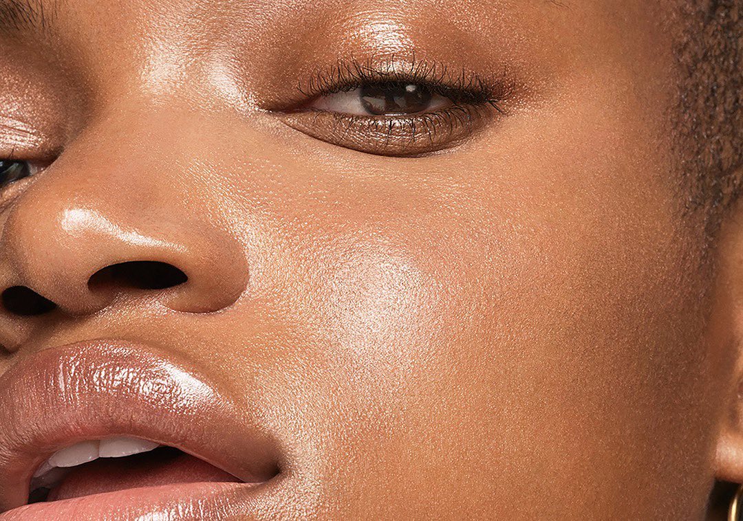 Close-up of an adult woman with tan skin, glossy lips, and brown eye makeup. The image is well-lit, highlighting the skin texture.