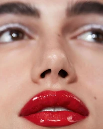Extreme close up beauty portrait of a woman with glossy red lipstick and white eyeliner photographed by Sarah Silver.