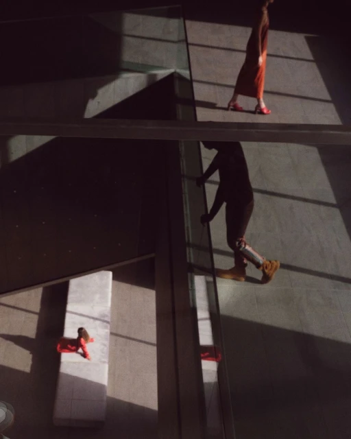 Low angle shot of two people walking on elevated walkways in a modern building, casting strong geometric shadows on the floor.