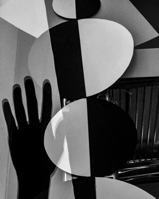 High-contrast black-and-white photography featuring geometric shapes, including circles and rectangles, with a human hand silhouette visible.