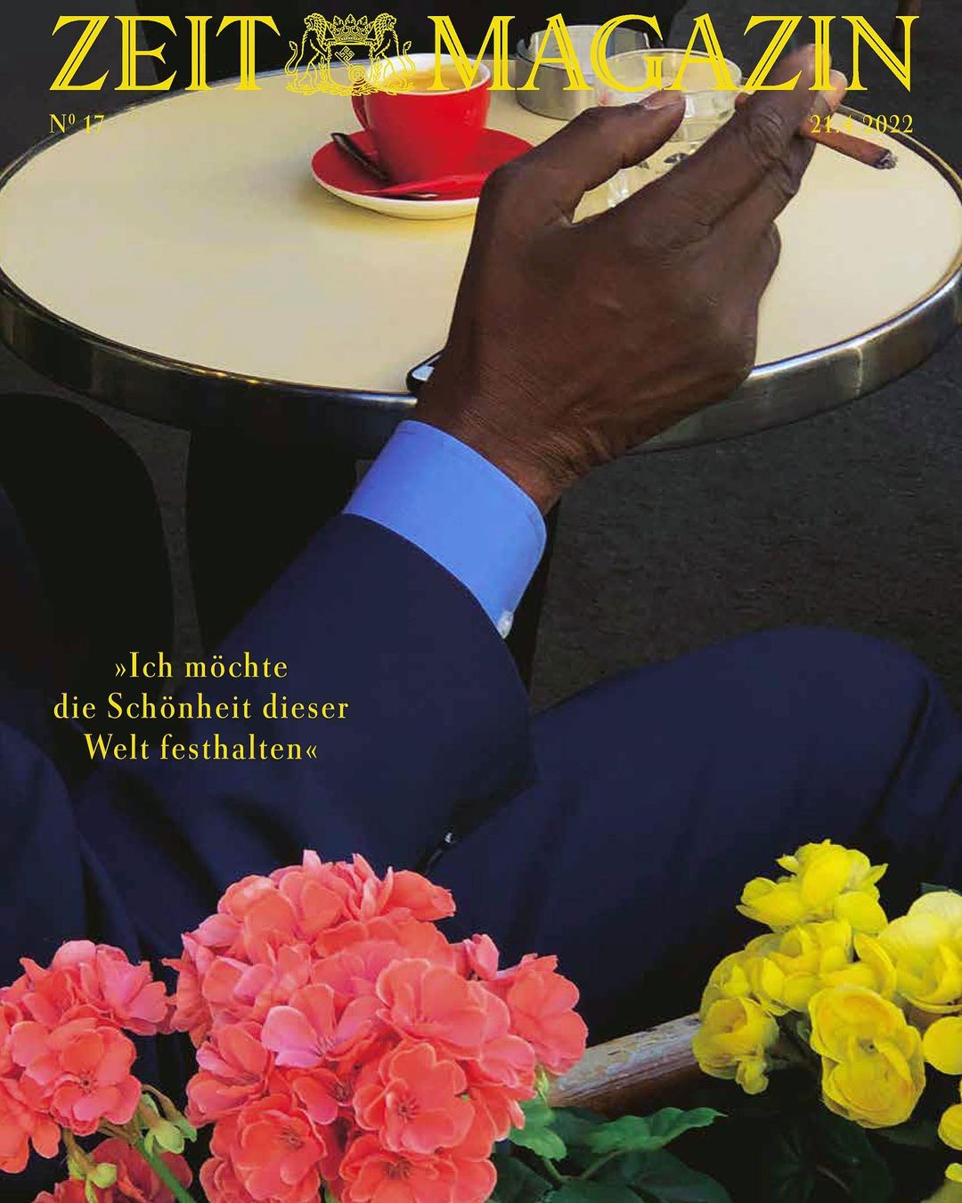 Magazine cover featuring a man's hand holding a cigarette, a cup of coffee, and floral arrangements in the foreground.