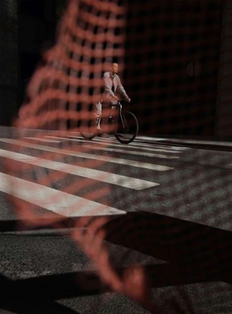 A man on a bicycle crossing a crosswalk, shadowed by an abstract red pattern in an urban environment with dark street aesthetic.