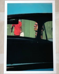 Two people viewed through a car windshield and rear window in an urban street setting in London