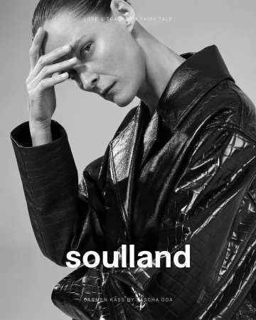 Model Carmen Kass in black leather coat with hand on forehead in black and white photography by Sascha Oda