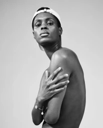 Black-and-white portrait of a man wearing a cap and a charm bracelet, photographed by Sascha Oda in Paris.