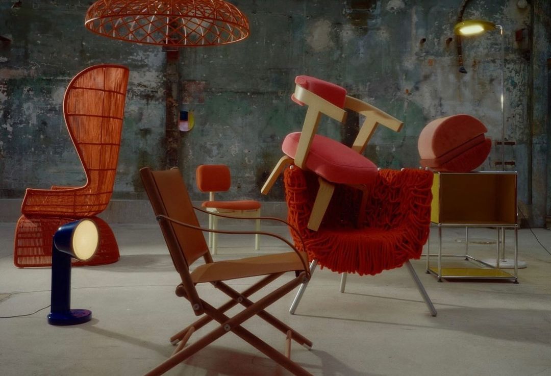 Eclectic interior with orange woven armchair, folding chair, blue lamp, and a modern lamp with a yellow shade on a textured wall.