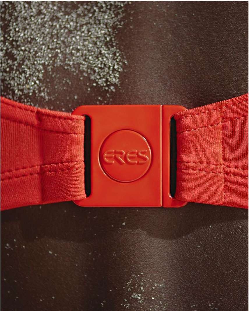 Close-up shot of a red Eres swimsuit clasp against dark skin and textured background, showcasing swimwear detail.