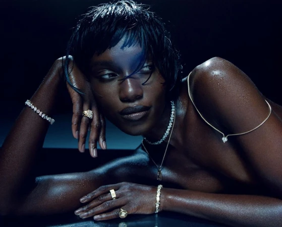 Elegant black woman with wet hair poses with diamond jewelry against a dark background. Jewelry includes rings, bracelet, and necklace.