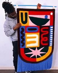 Black man holding a large colorful tufted rug featuring abstract geometric shapes and blue fringe in Paris by illustrator Saturn.
