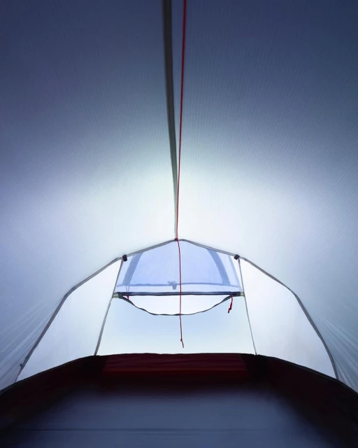 Interior view of a white camping tent with a window opening to the outdoors, showcasing camping equipment and outdoor recreation.