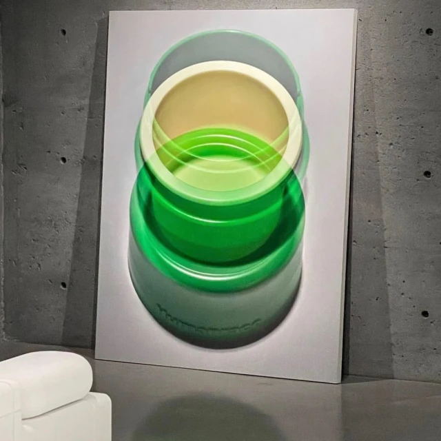 A green-and-cream colored abstract art print hangs on a gray wall, depicting overlapping green and cream bowls in a blurred style.