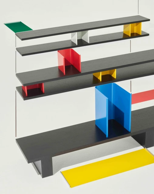 Abstract shot of a geometric design featuring black shelves and red, blue, green, and yellow vertical color blocks on a white background.