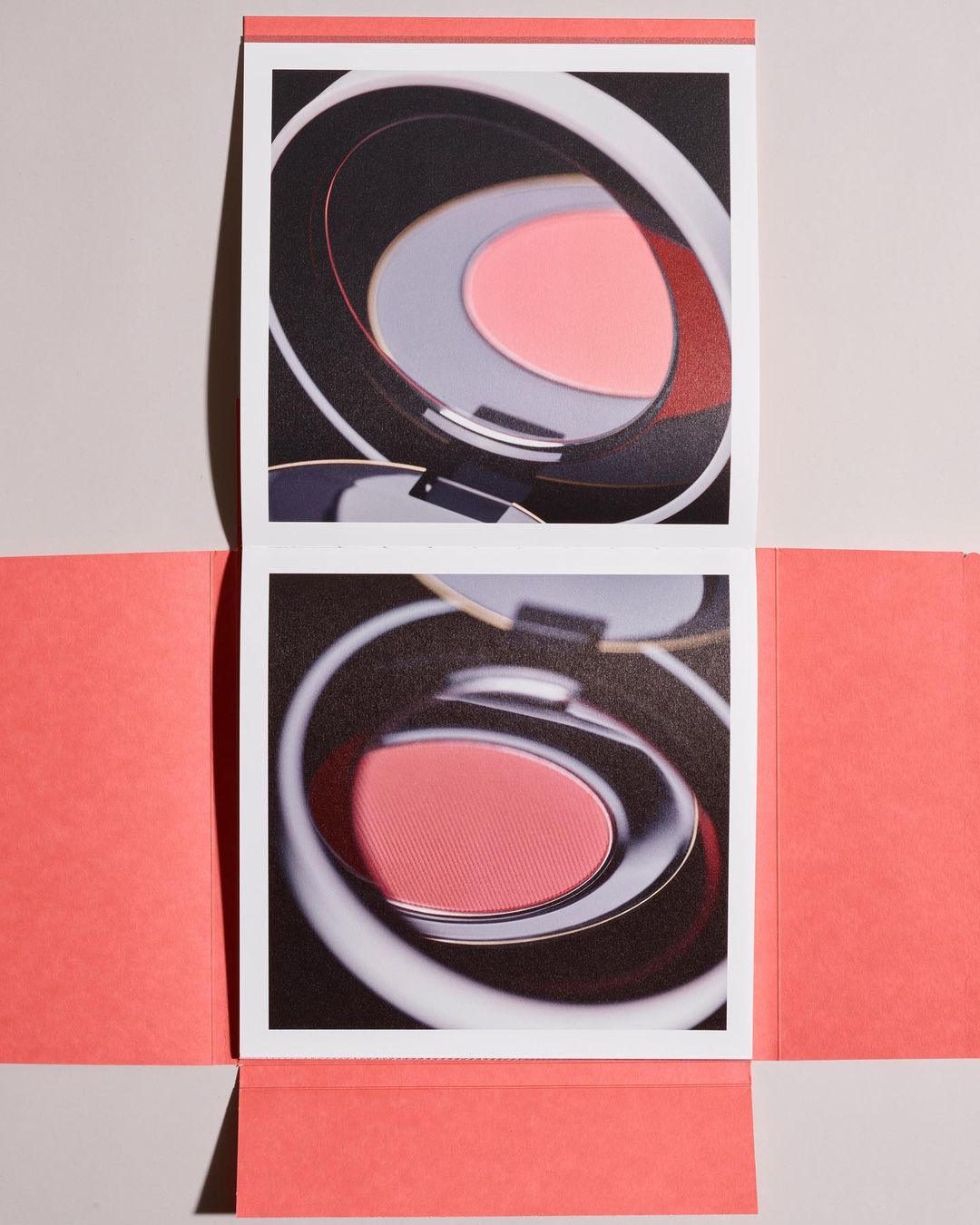 Still life of two square cosmetic containers, one open and one closed, presented on a peach and white backdrop.