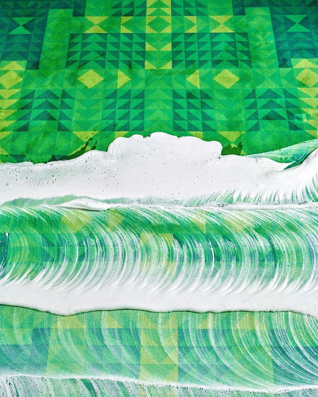 Abstract green geometric pattern with foamy white streaks creating a textured, vibrant visual effect. Dominant green hues.