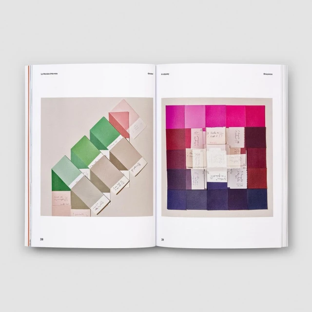 Open book displaying color palette swatches in shades of green, pink, red, and purple, arranged with hand-written paper notes.