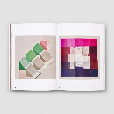Open book displaying color palette swatches in shades of green, pink, red, and purple, arranged with hand-written paper notes.
