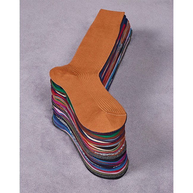 Stack of assorted socks with a tan sock on top, neatly piled on a gray surface, highlighting textile and fashion.
