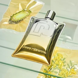 Gold metallic perfume bottle on glass shelf alongside vacuum-sealed produce packs photographed by Scheltens & Abbenes.